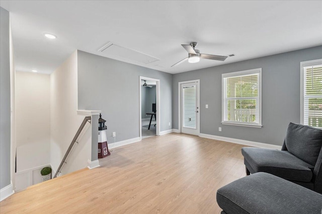 sitting room featuring light wood finished floors, attic access, baseboards, and an upstairs landing