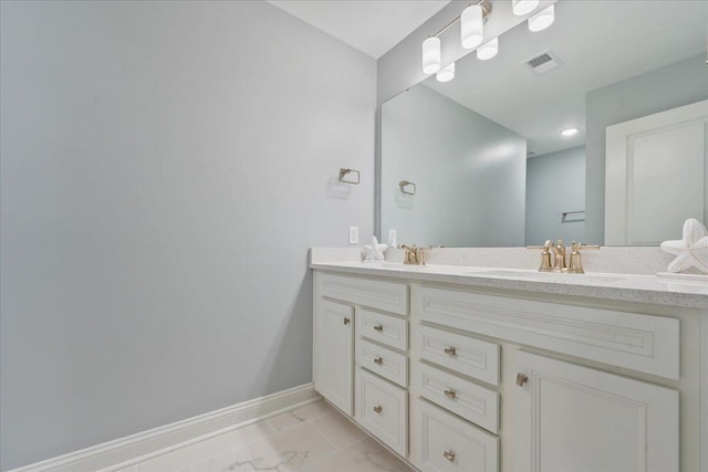 full bathroom featuring marble finish floor, a sink, baseboards, and double vanity