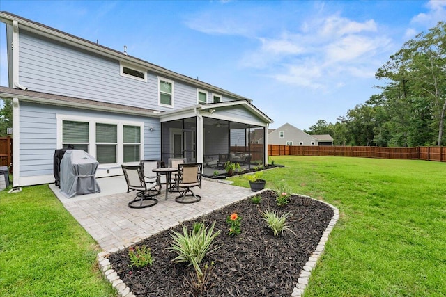 rear view of property with a yard, a patio area, fence private yard, and a sunroom