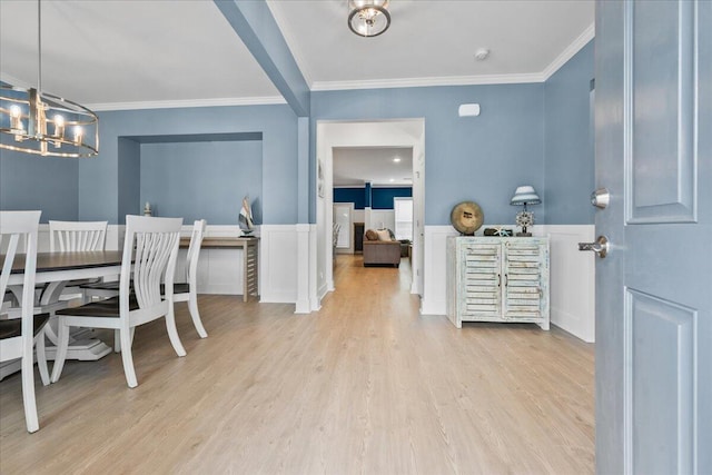 dining room featuring wood finished floors, a wainscoted wall, crown molding, and an inviting chandelier