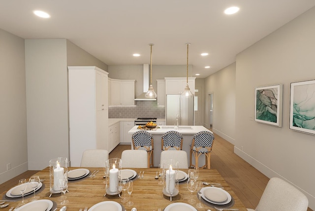 kitchen featuring backsplash, a kitchen bar, a center island, wall chimney range hood, and light wood-type flooring