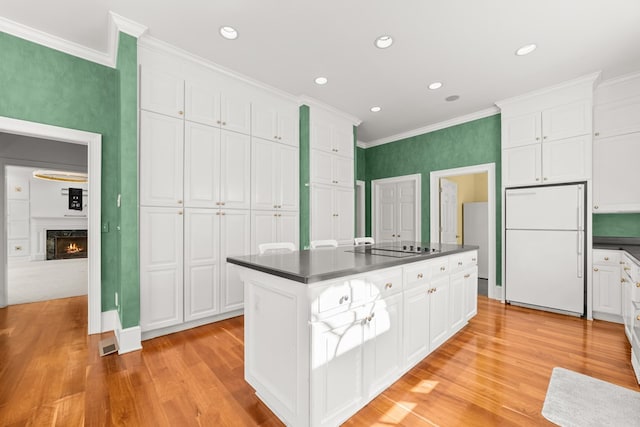 kitchen with white refrigerator, white cabinetry, and light hardwood / wood-style floors