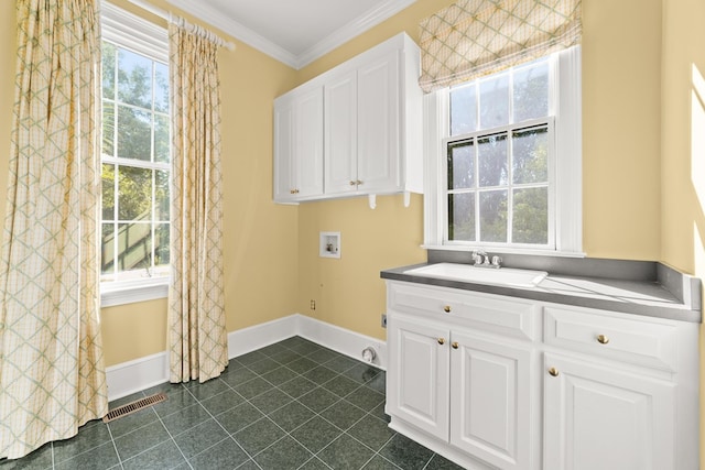 laundry room with dark tile patterned flooring, sink, cabinets, hookup for a washing machine, and crown molding