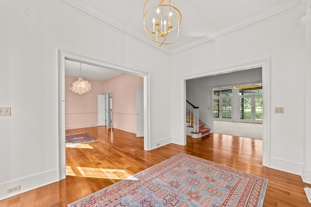 entrance foyer with a notable chandelier, crown molding, and hardwood / wood-style flooring