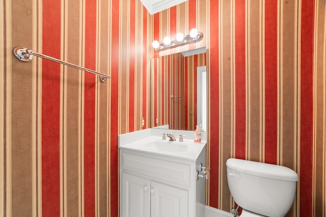 bathroom with ornamental molding, vanity, and toilet