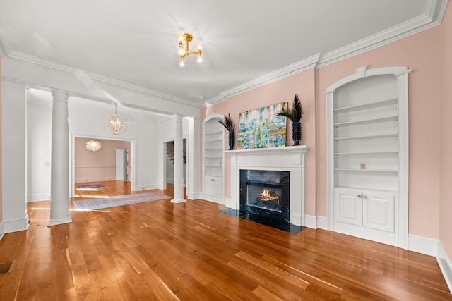 unfurnished living room featuring wood-type flooring, a premium fireplace, ornate columns, crown molding, and built in shelves