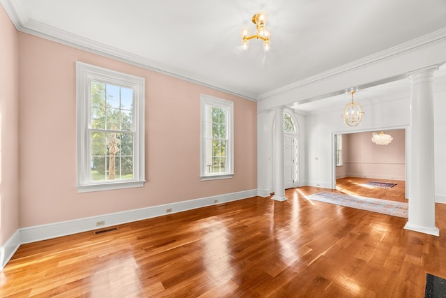 unfurnished room featuring an inviting chandelier, crown molding, and hardwood / wood-style floors