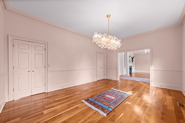 unfurnished dining area featuring ornamental molding, a notable chandelier, and hardwood / wood-style floors