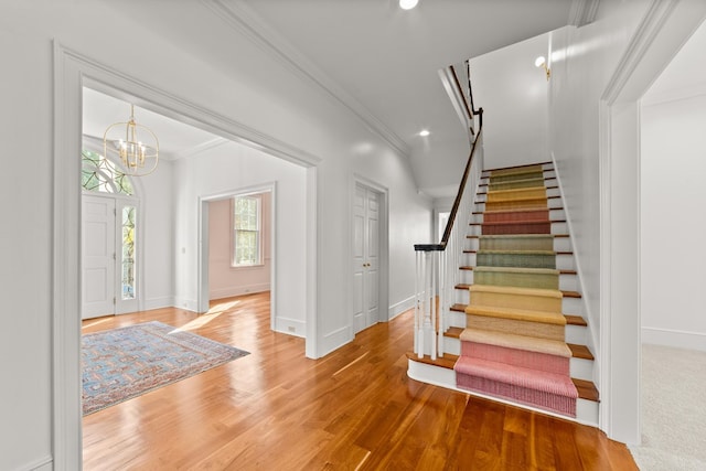 foyer entrance featuring wood-type flooring, a notable chandelier, a barn door, and ornamental molding