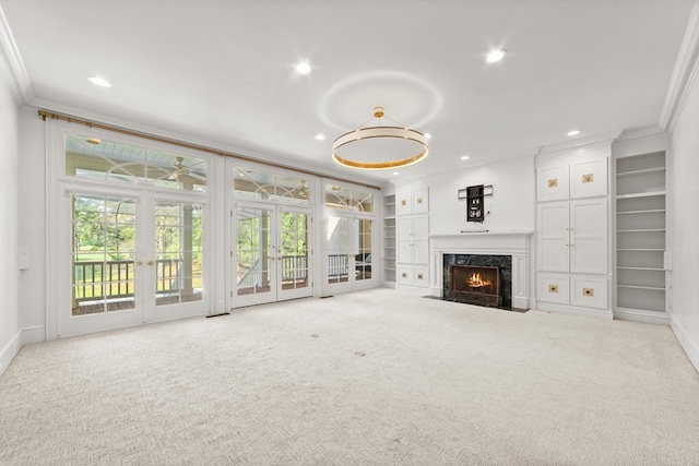 unfurnished living room featuring a fireplace, french doors, light colored carpet, and ornamental molding