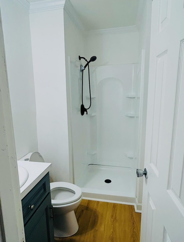 full bathroom with a shower stall, wood finished floors, vanity, and ornamental molding