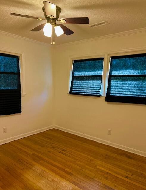 spare room featuring a textured ceiling, wood finished floors, and crown molding