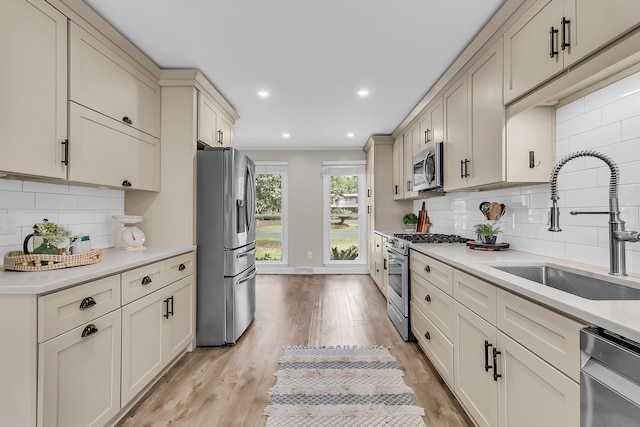 kitchen featuring tasteful backsplash, light wood-style flooring, a sink, stainless steel appliances, and light countertops