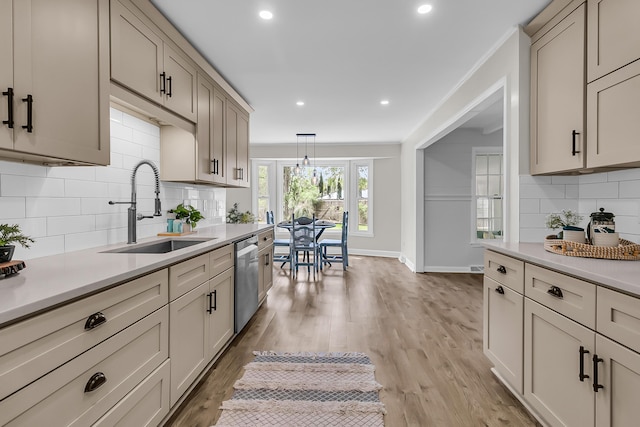 kitchen with a sink, light countertops, baseboards, dishwasher, and backsplash