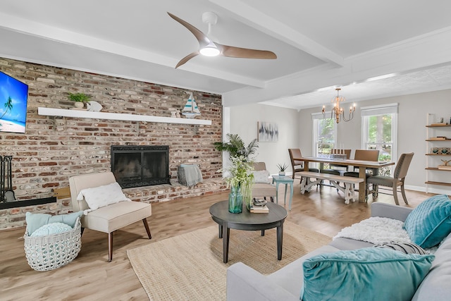 living area featuring a fireplace, light wood-style floors, beamed ceiling, and ceiling fan with notable chandelier