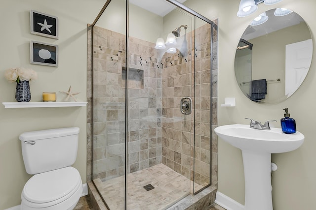 full bath featuring toilet, baseboards, a stall shower, and a sink