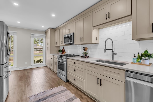kitchen with tasteful backsplash, stainless steel appliances, light countertops, and a sink