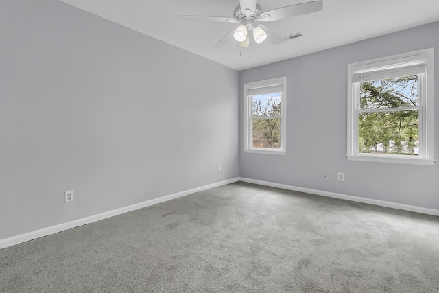 spare room featuring carpet floors, visible vents, a ceiling fan, and baseboards