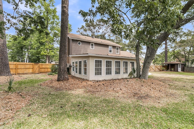 rear view of house featuring fence and a yard