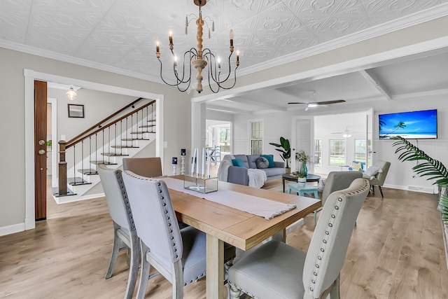 dining space featuring light wood-style flooring, stairway, baseboards, beam ceiling, and ceiling fan with notable chandelier