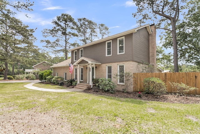 view of front of house featuring fence, a chimney, a front yard, and brick siding