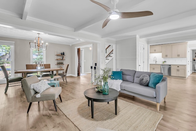 living room with beam ceiling, stairway, ceiling fan with notable chandelier, and light wood finished floors