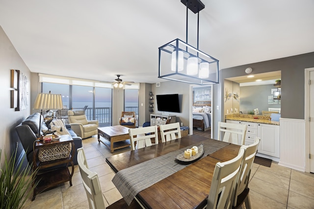 tiled dining area featuring expansive windows and ceiling fan