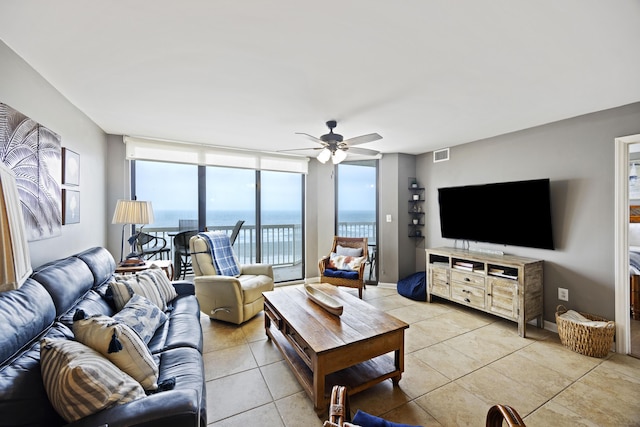 tiled living room with ceiling fan and floor to ceiling windows