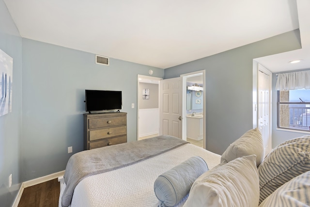 bedroom featuring ensuite bath and dark wood-type flooring