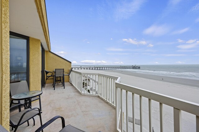 balcony with a water view and a view of the beach