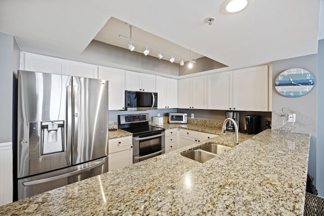 kitchen featuring white cabinetry, sink, kitchen peninsula, stainless steel appliances, and light stone countertops