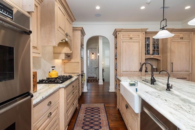 kitchen featuring light stone counters, pendant lighting, stainless steel appliances, and ornamental molding