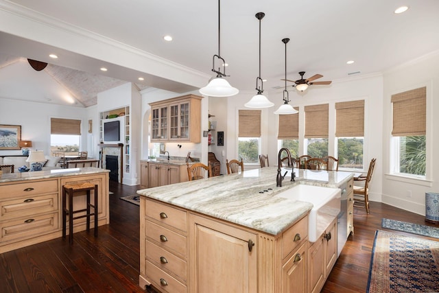 kitchen with a kitchen breakfast bar, ceiling fan, light brown cabinets, decorative light fixtures, and a large island