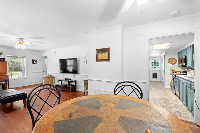 dining space featuring dark hardwood / wood-style flooring, a skylight, ceiling fan, and ornamental molding