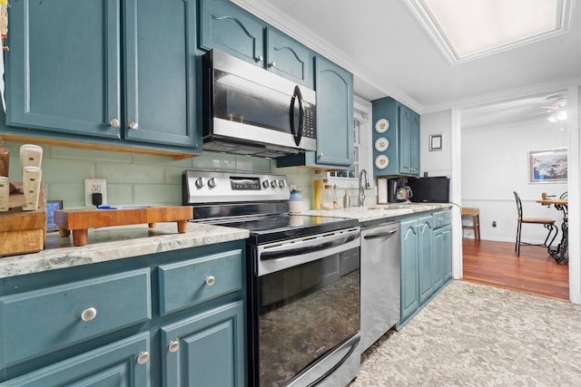 kitchen with sink, stainless steel appliances, blue cabinets, crown molding, and hardwood / wood-style floors