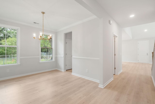 spare room with a healthy amount of sunlight, ornamental molding, light hardwood / wood-style floors, and a notable chandelier