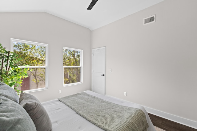 bedroom with lofted ceiling, visible vents, a ceiling fan, wood finished floors, and baseboards