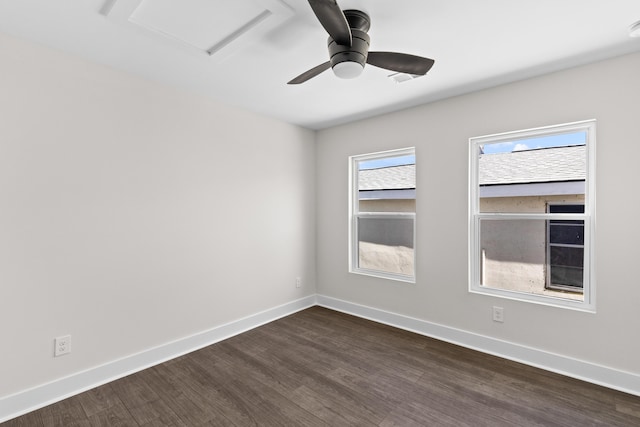 unfurnished room with dark wood-type flooring, attic access, a ceiling fan, and baseboards