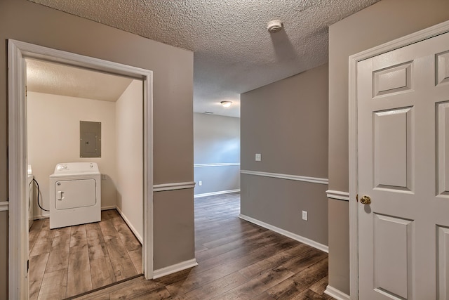 corridor with a textured ceiling, hardwood / wood-style flooring, baseboards, independent washer and dryer, and electric panel