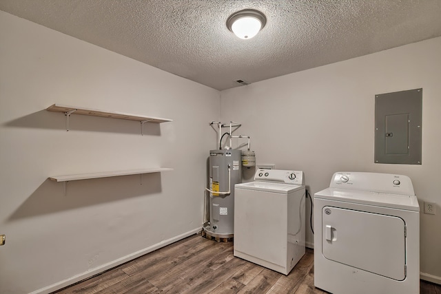 clothes washing area with electric water heater, a textured ceiling, electric panel, washing machine and dryer, and hardwood / wood-style flooring