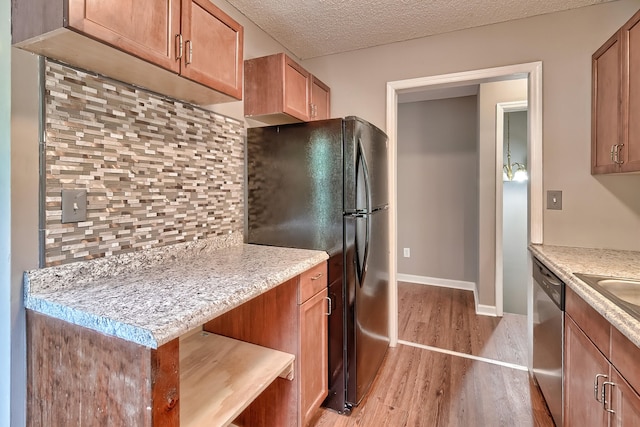 kitchen with tasteful backsplash, dishwasher, freestanding refrigerator, a textured ceiling, and light wood-type flooring