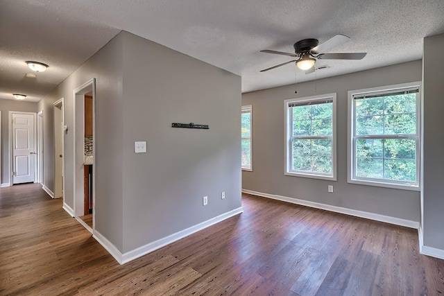 unfurnished room featuring dark wood finished floors, a textured ceiling, and baseboards