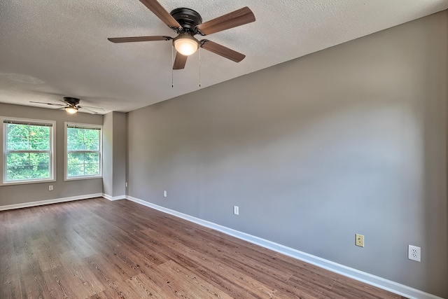 empty room featuring dark wood finished floors, a textured ceiling, and baseboards