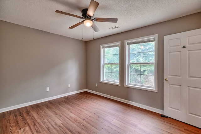 unfurnished room featuring baseboards, a textured ceiling, visible vents, and wood finished floors