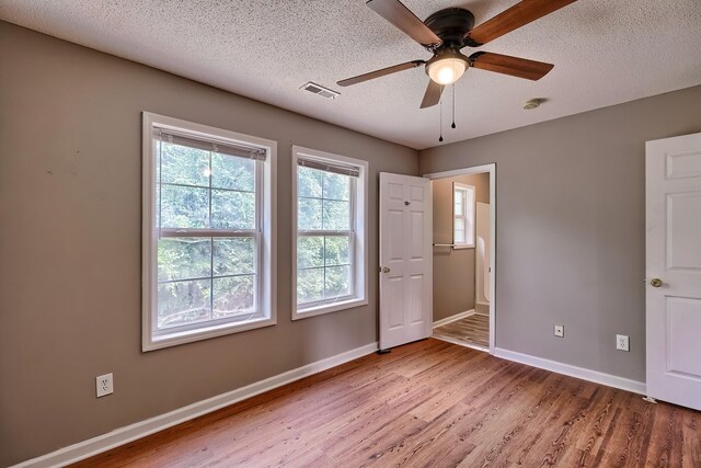 unfurnished room with a textured ceiling, plenty of natural light, ceiling fan, and hardwood / wood-style floors