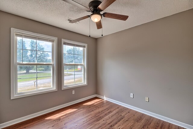 spare room featuring light wood-type flooring, ceiling fan, and a textured ceiling