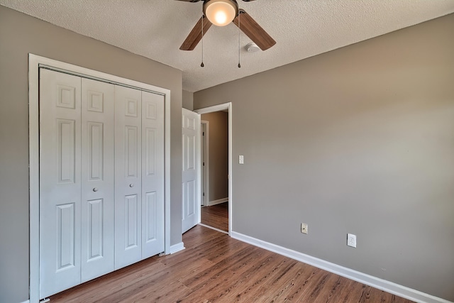 unfurnished bedroom featuring baseboards, ceiling fan, wood finished floors, a textured ceiling, and a closet