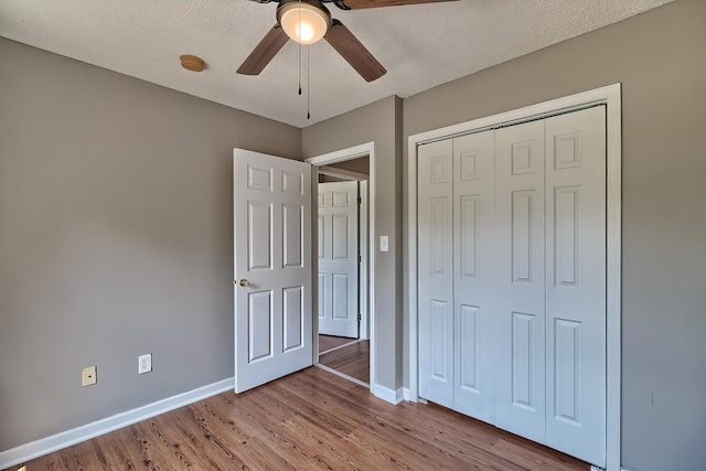 unfurnished bedroom featuring a textured ceiling, ceiling fan, wood finished floors, baseboards, and a closet