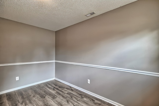 unfurnished room featuring visible vents, a textured ceiling, baseboards, and wood finished floors