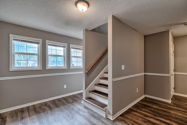 staircase featuring a textured ceiling, baseboards, and wood finished floors